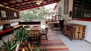 Un patio acogedor con un banco de madera, una mesa de comedor con sillas y una alfombra a rayas.