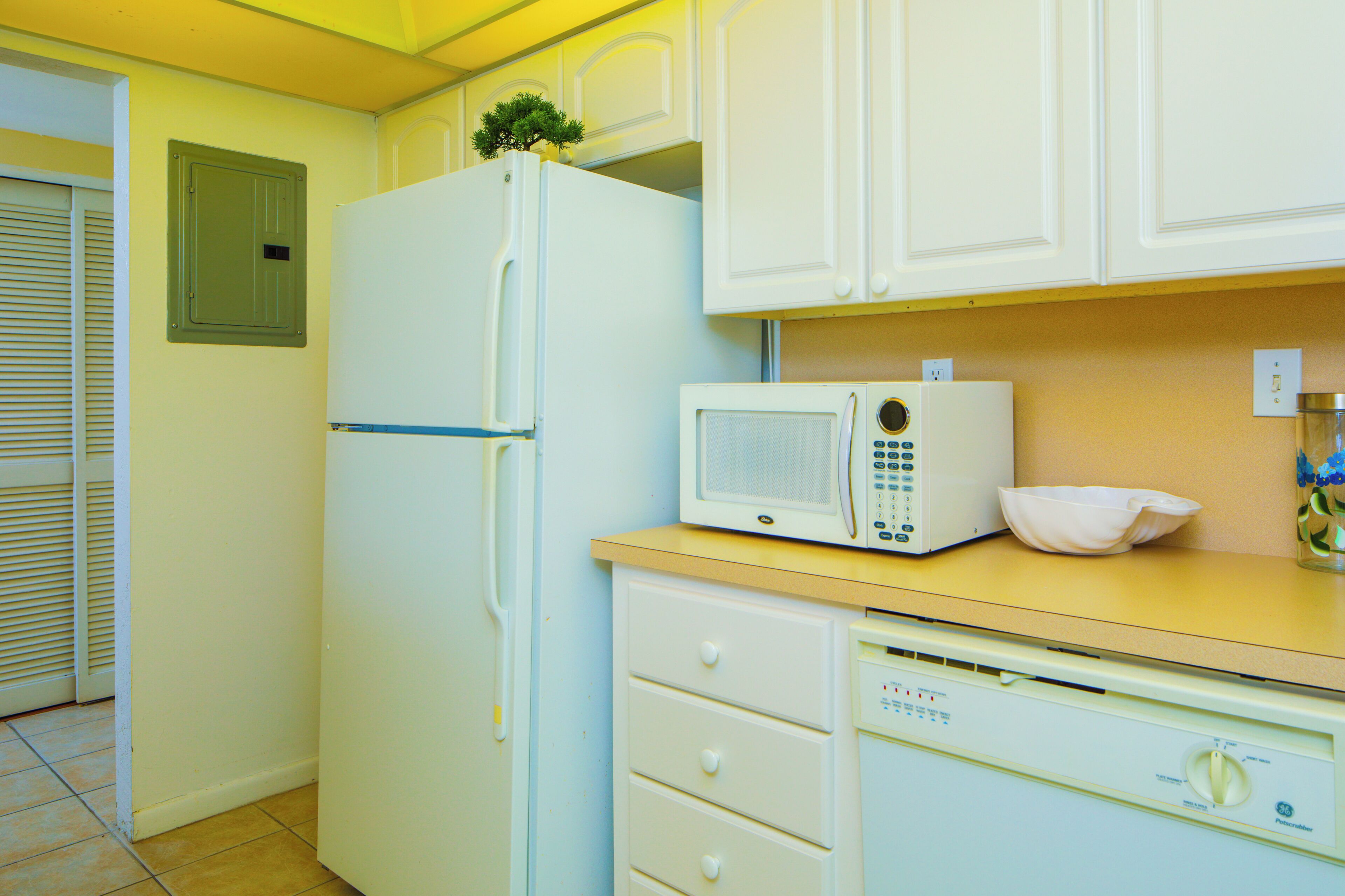 A compact kitchen with white appliances, including a refrigerator, microwave, and dishwasher.