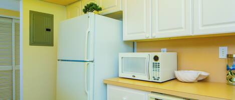 A compact kitchen with white appliances, including a refrigerator, microwave, and dishwasher.