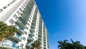 Un grand hôtel moderne doté de nombreux balcons et surplombant un ciel d’un bleu éclatant.