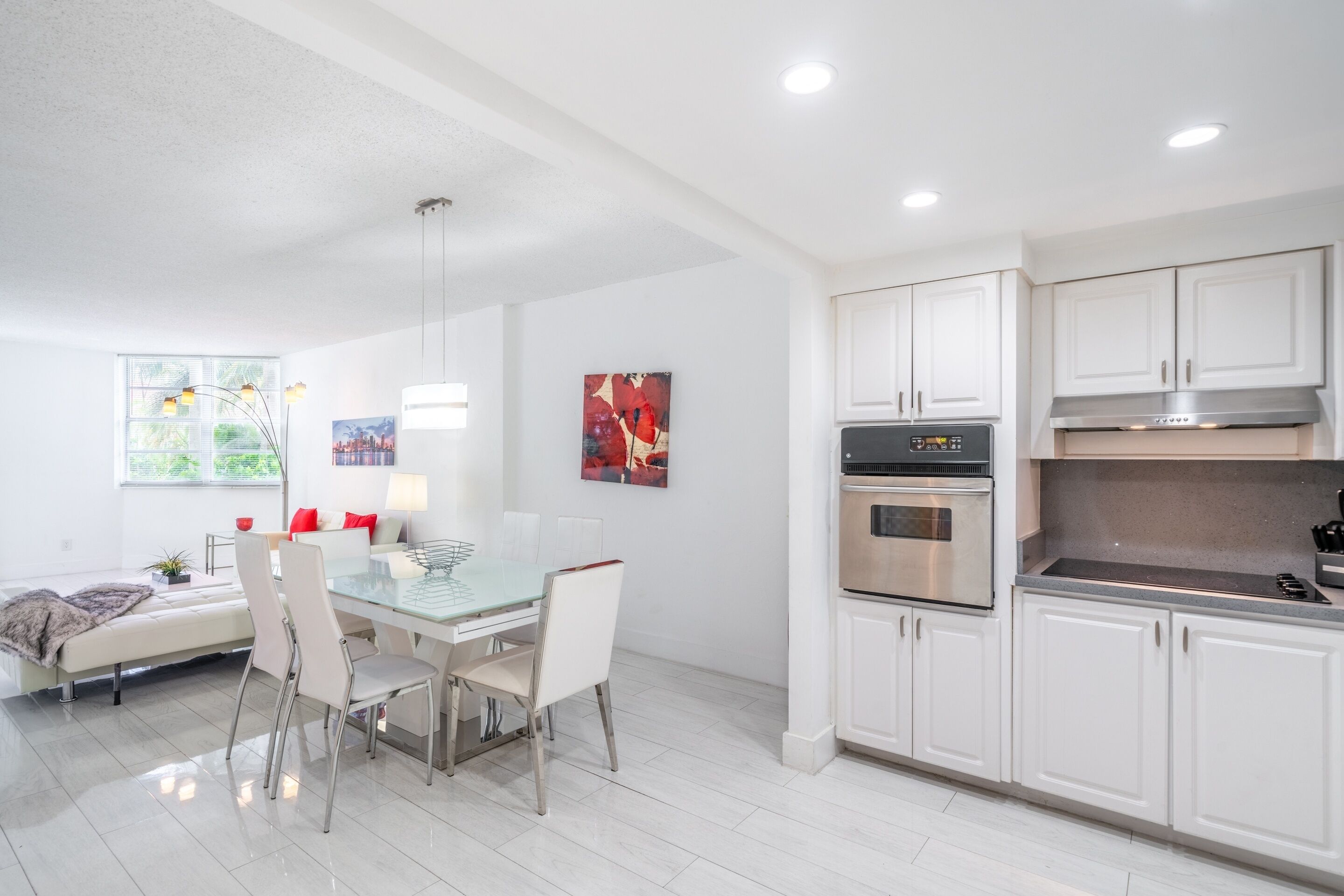 A modern kitchen with white cabinets, stainless steel appliances, and a glass dining table.