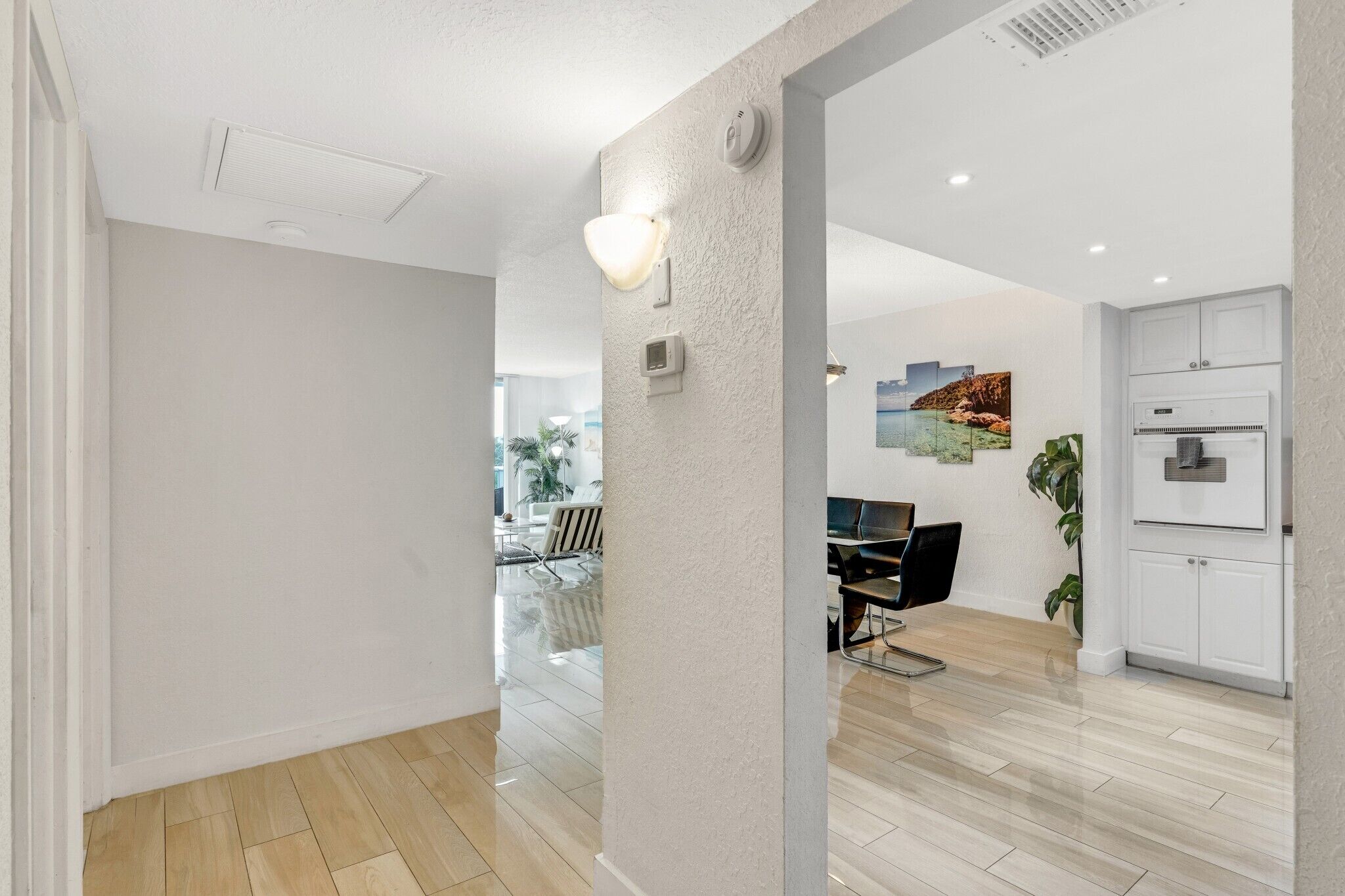 A modern interior with a kitchen, dining area, and a hallway leading to a living space.