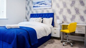 A bedroom with a bed, a desk, a chair, and a painting on the wall. - Cosy 3 Bedroom House Set In Manchester Free wifi & private parking (Greater Manchester)