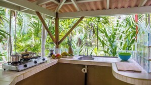 A kitchen with a gas stove, sink, and window overlooking a tropical garden. - LA PONDEROSA Beach & Jungle Resort (Pavón)