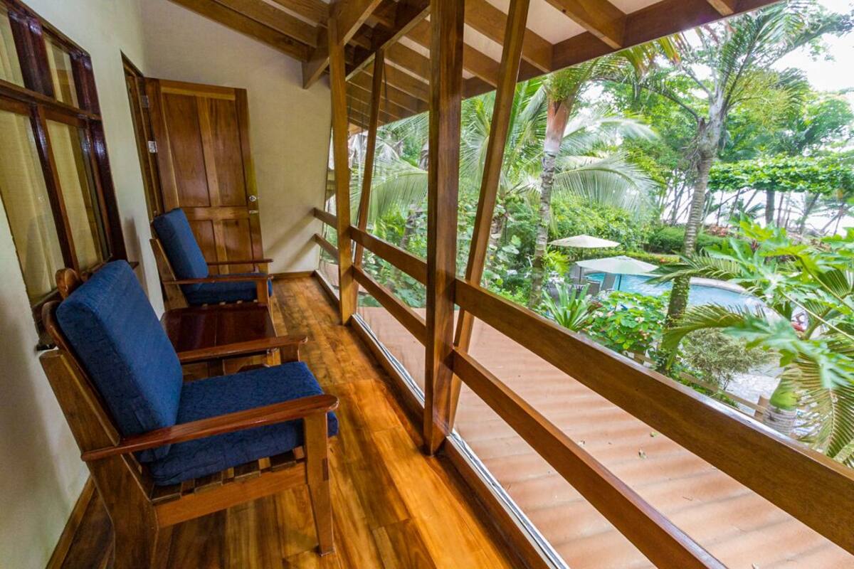 A wooden balcony with two blue cushioned chairs and a wooden door.