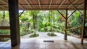 A covered outdoor area with a stone floor, surrounded by lush tropical plants and a view of dense greenery. - LA PONDEROSA Beach & Jungle Resort (Pavón)