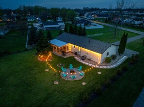 Ein Wohnhaus mit Terrasse, Außenbeleuchtung und Rasenfläche.