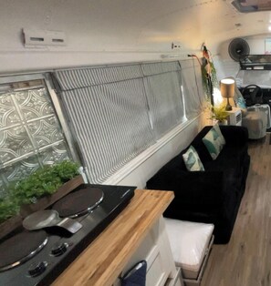 A compact kitchen with a stove, a small sink, and a window with decorative metal grilles.