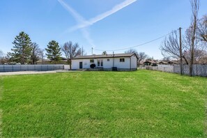 A single-story house with a front porch, a well-maintained lawn, and a clear sky.