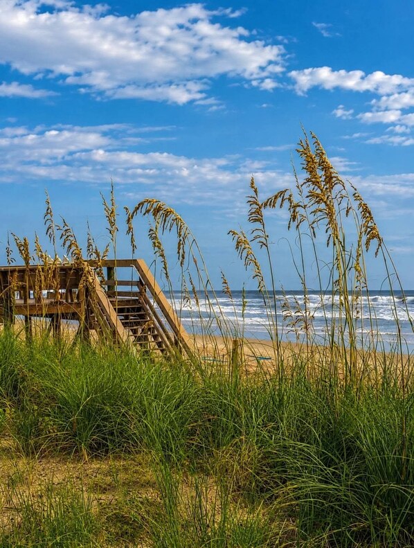 A beach with a wooden staircase leading to a platform, overlooking the ocean.