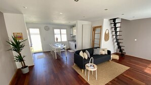 A spacious living area with a black sofa, a dining table, and a staircase. - Superbe Maison - Biarritz/plage (Biarritz)