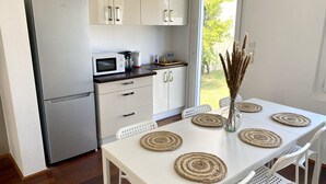 A modern kitchen with white cabinets, a stainless steel refrigerator, a microwave, and a dining table with woven placemats. - Superbe Maison - Biarritz/plage (Biarritz)