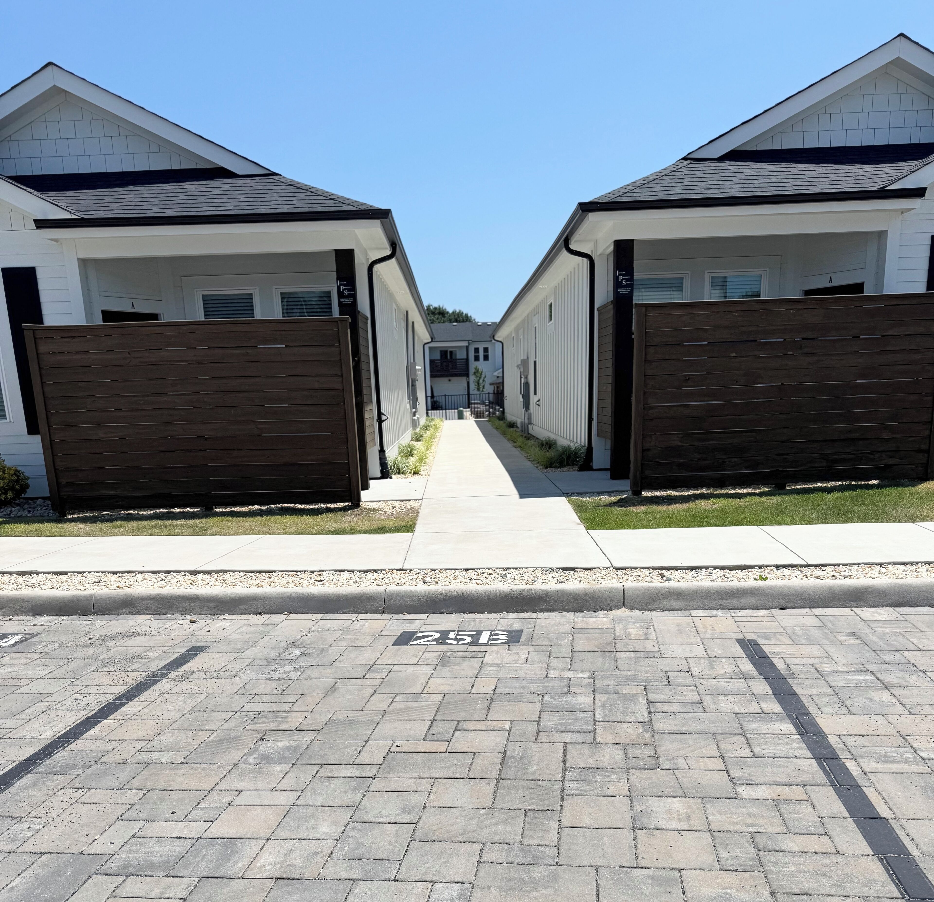 A row of modern, two-story houses with a central pathway leading to a gated entrance.
