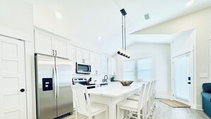 Una cocina moderna con armarios blancos, electrodomésticos de acero inoxidable y una isla central con sillas.