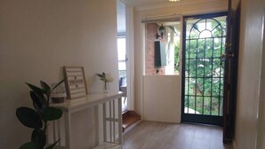 A hallway with a white bench, a potted plant, and a door leading outside. - Happy & Spacious Home (nr hospital) @Garran (Garran)