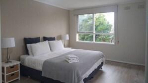 A bedroom with a bed, nightstands, a ceiling fan, and a window with a view of trees. - Happy & Spacious Home (nr hospital) @Garran (Garran)