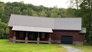 Eine rustikale Holzhütte mit einem Metalldach, Steinpfeilern und einem Schotterweg.