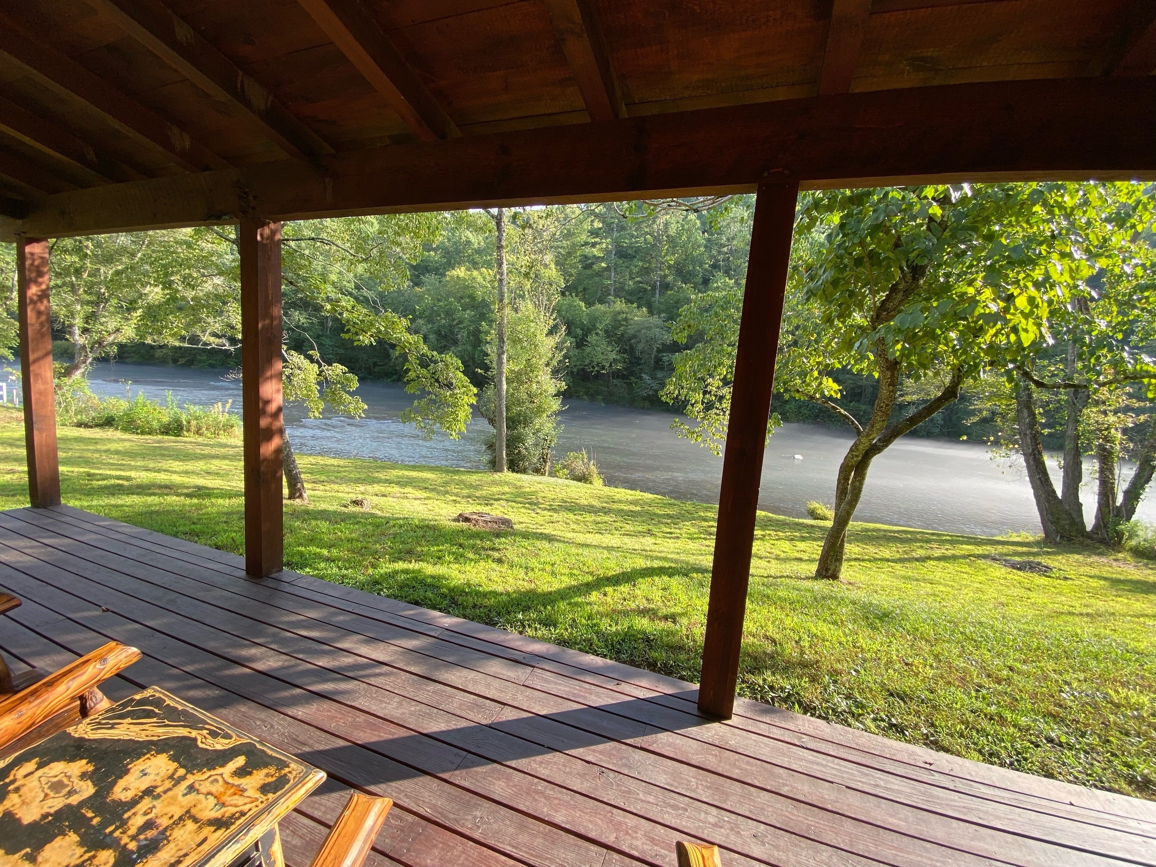 A wooden deck with a view of a river and trees.