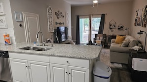 Una cocina moderna con muebles blancos, encimera de granito y lavavajillas integrado.