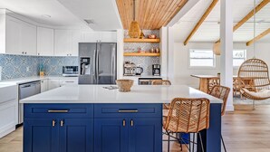 Une cuisine moderne dotée d’un îlot central, de meubles blancs et d’un mur d’accent bleu.