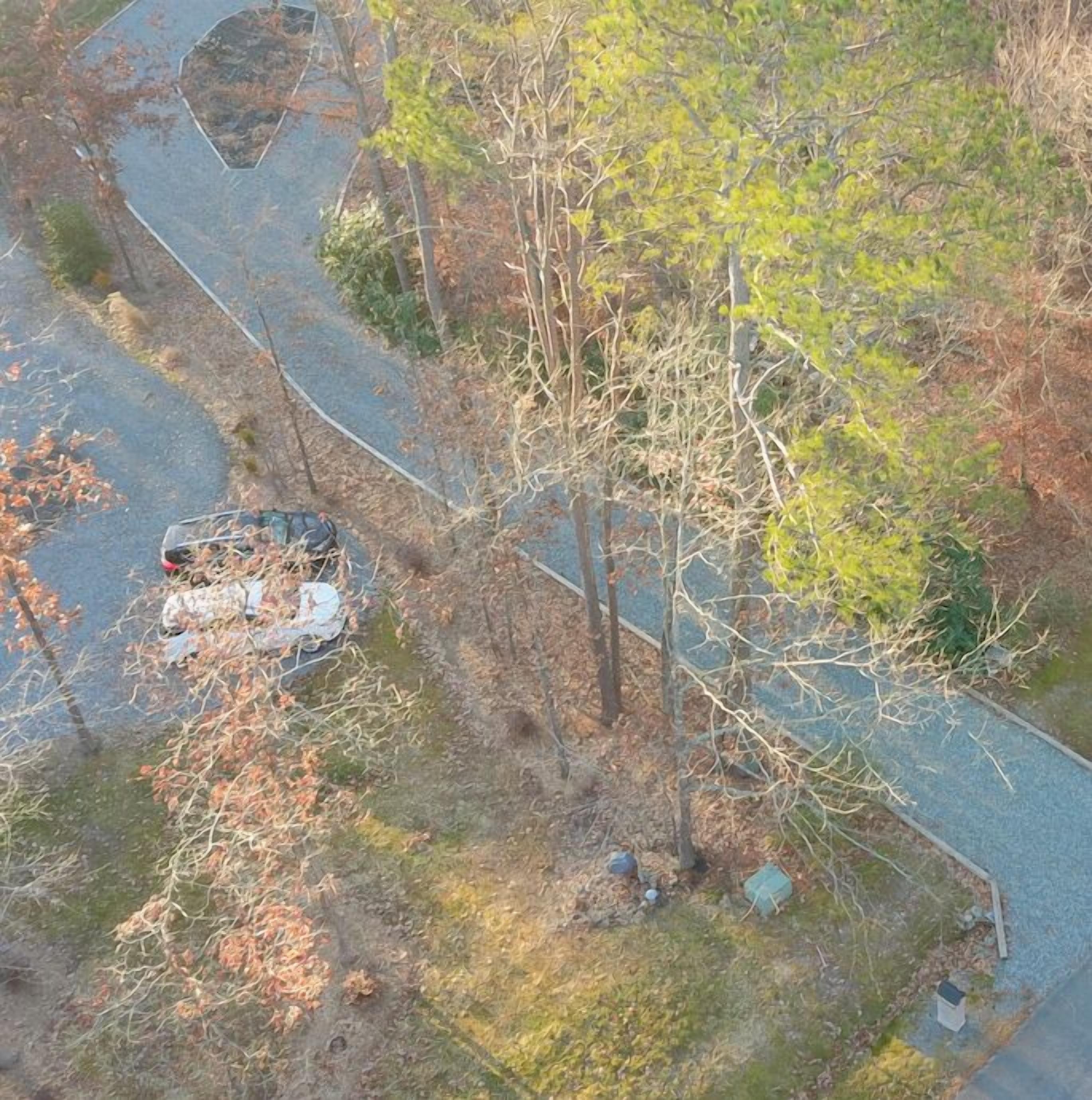 An aerial view of a winding road with a vehicle parked on the side.