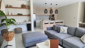 A modern living room with a grey sofa, a coffee table, and a potted plant. - Villa Varia (Rarotonga)