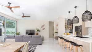 A modern kitchen with a white countertop, black bar stools, and a built-in oven. - Villa Varia (Rarotonga)