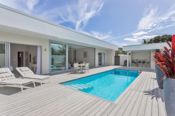 Een buitenzwembad, ligstoelen bij het zwembad