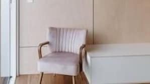 Habitació moderna amb disseny minimalista, que presenta un sofà de tons clars, una taula petita i una estant mural amb un objecte decoratiu.