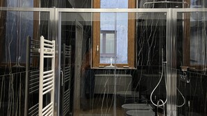 A modern bathroom with a glass-enclosed shower, a white bathtub, and a vanity with a sink. - Families, groups of friends, looking for a comfortable apartment in the Acese Baroque (Acireale)