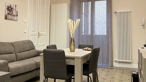 A modern living room with a sofa, dining table, chairs, and a vase with dried flowers. - Families, groups of friends, looking for a comfortable apartment in the Acese Baroque (Acireale)