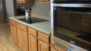 Una cocina con armarios de madera, horno de acero inoxidable y encimera de granito.