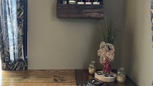 Una mesa de comedor de madera con diseño rústico, una estantería de pared para vinos con varias botellas, y un jarrón decorativo con un lazo en la pared.