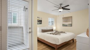 A bedroom with a bed, a ceiling fan, and artwork on the walls. - Ocean View Perfection - Parking, W/D, Pet Friendly & Steps to Sand (Mission Beach)