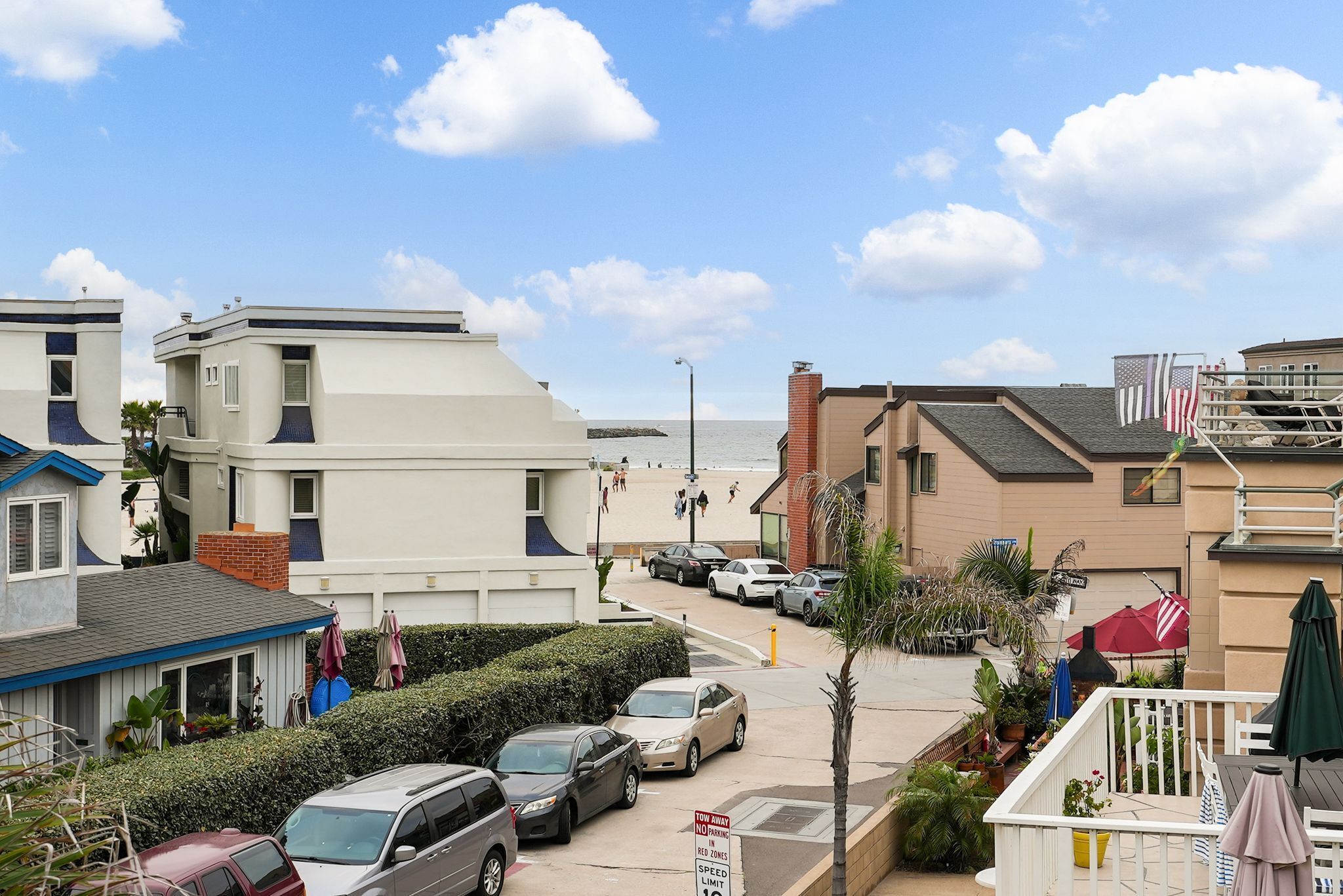 A coastal residential area with houses, parked cars, and a clear sky.