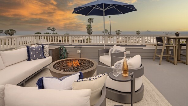 A rooftop terrace with a fire pit, outdoor seating, and a view of the ocean at sunset. - Designer Luxury Coastal Home with Panoramic Ocean Views, Rooftop Deck, & Fire Pit (La Jolla)