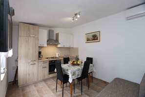 A compact kitchen with a dining area, a coffee maker, and a fruit bowl on the table. - Holiday home in a private olive grove (Šilo)