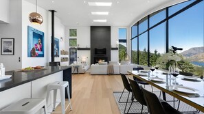 A modern kitchen with a large island, a dining area with a view, and a living space with a fireplace.