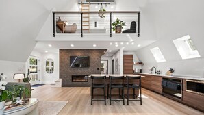 Eine moderne Loftwohnung mit Küche, Essbereich und einem Schlafzimmer im oberen Bereich mit Balkon.