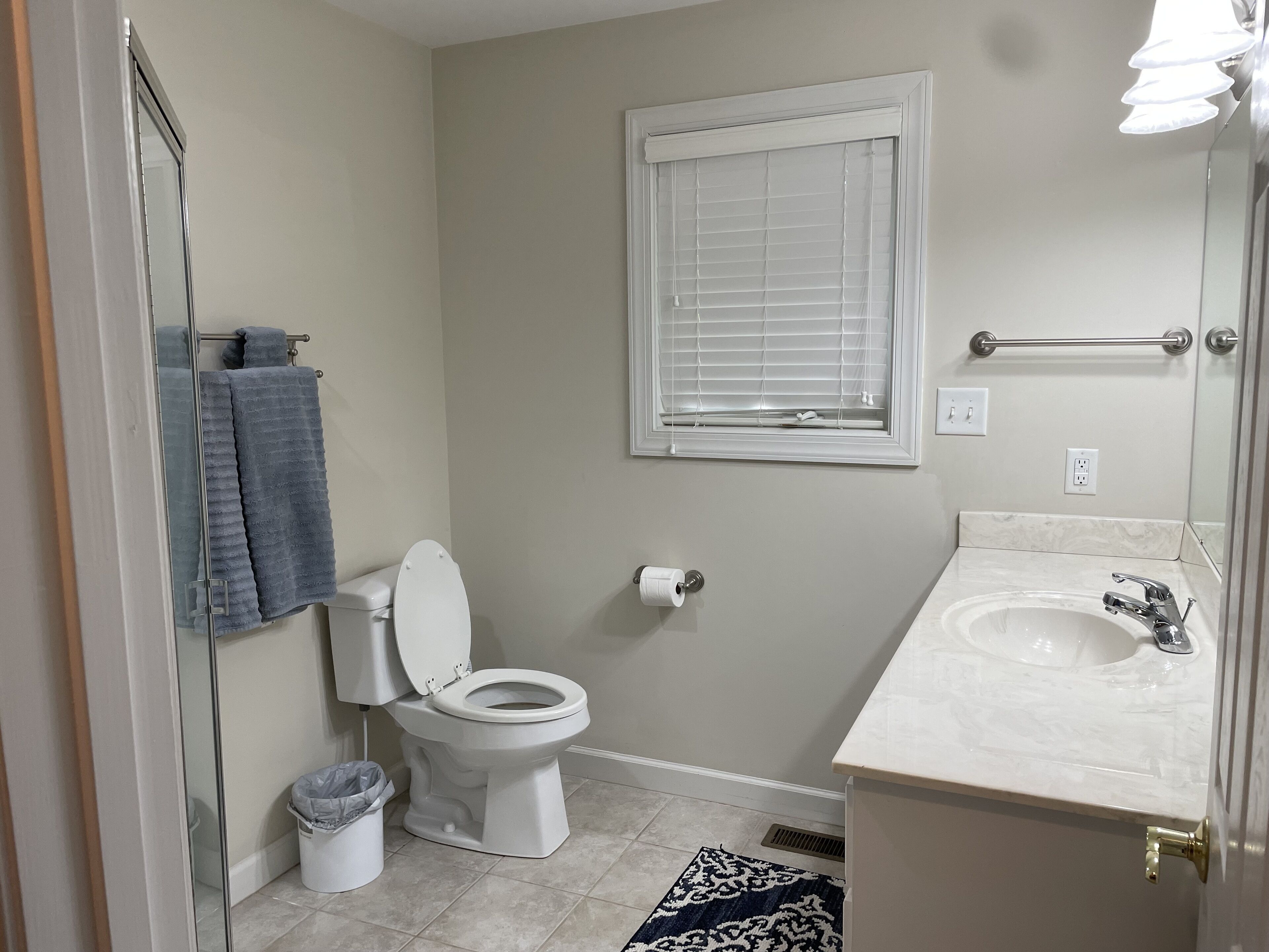 A bathroom with a toilet, sink, and window.