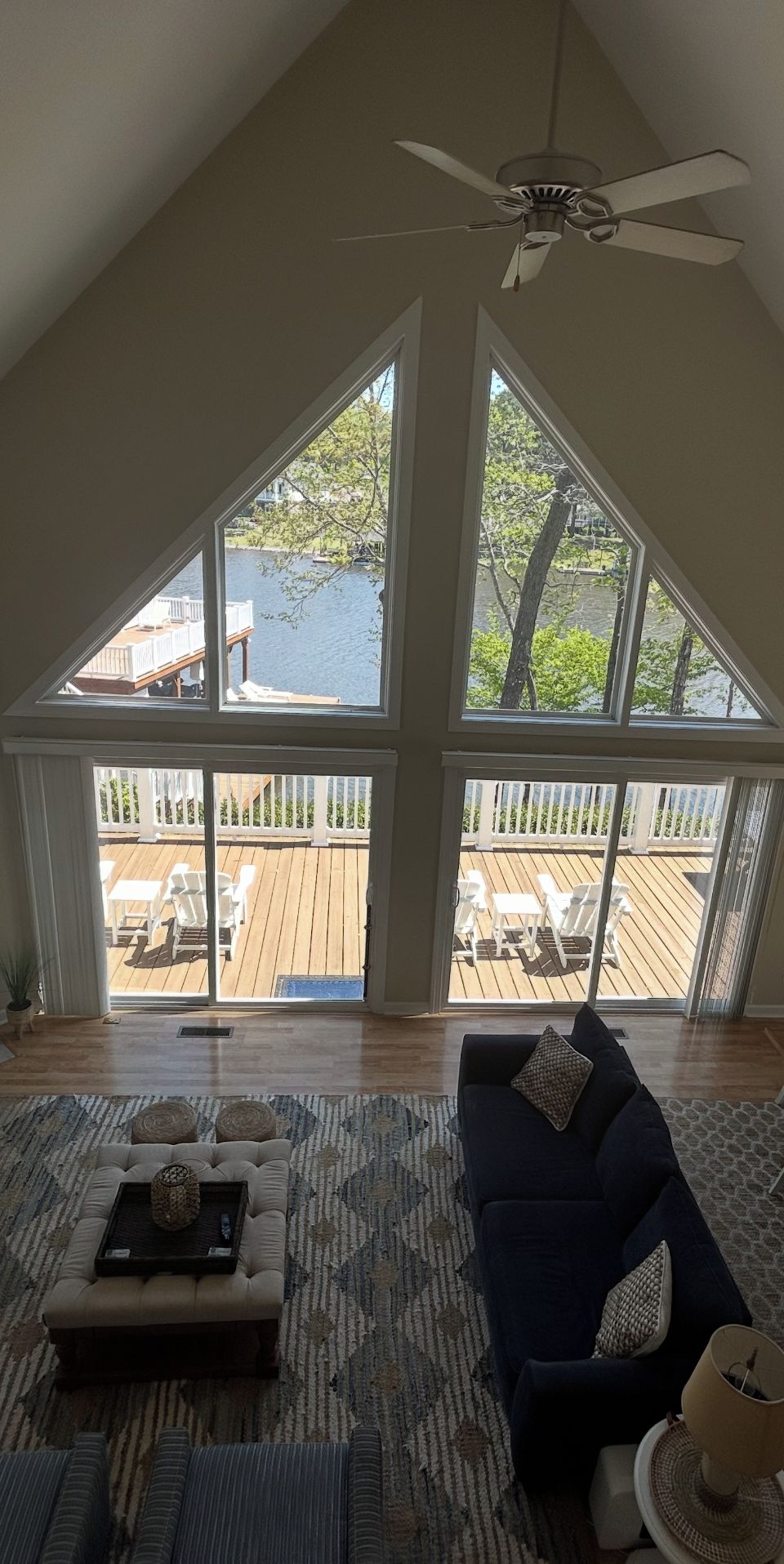 A spacious living room with a large window overlooking a wooden deck and a body of water.