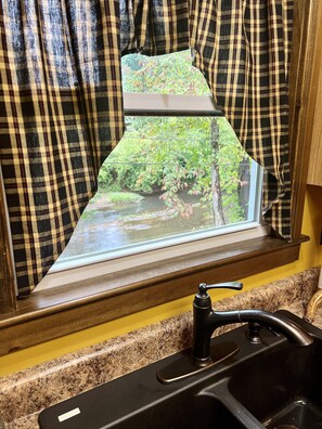 A kitchen with a granite countertop, a black faucet, and a window with a view of a forest. - 2BR-1B. Fire Pit With Stunning River View. Minutes From Downtown Huntington. (Kenova)