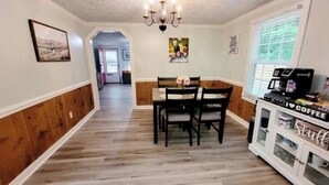 A dining area with a wooden floor, a dining table with chairs, a chandelier, and a coffee station. - Beautiful Cottage! 2.5m from I-95,13m to FtBragg (Fayetteville)