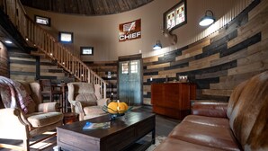 Un intérieur rustique avec un escalier en bois, des canapés en cuir et une table basse en bois.