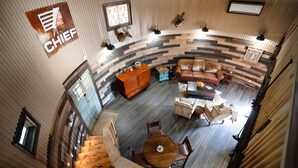Un vaste espace salon agrémenté d’un mur en bois incurvé, d’un escalier en bois et d’un coin salon avec un canapé en cuir marron et une table ronde en bois.