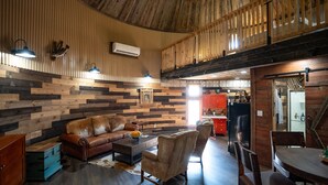 Un intérieur rustique avec un plafond en bois, un canapé en cuir, une table à manger et un coin cuisine doté de meubles rouges.