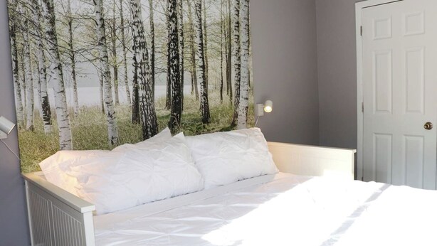 Un dormitorio con cama, lámpara de pared y una puerta.