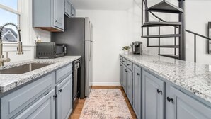 Una cocina moderna con armarios grises, encimera de granito, refrigerador de acero inoxidable y estufa empotrada.