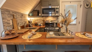 A kitchen with a wooden countertop, a stainless steel microwave, a stove, and a sink. - Quant carriage House, near the city of Asheville and Ashville Airport! (Arden)