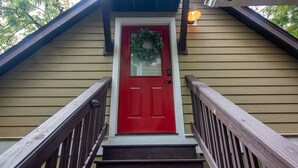 A red door with a wreath, wooden stairs, and a light fixture above. - Quant carriage House, near the city of Asheville and Ashville Airport! (Arden)